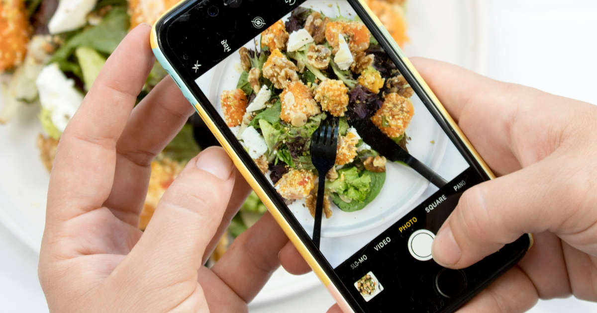 Nahaufnahme von Händen einer Person, die ein iPhone benutzt und ein Foto von einer Speise macht. (Foto: social.cut)